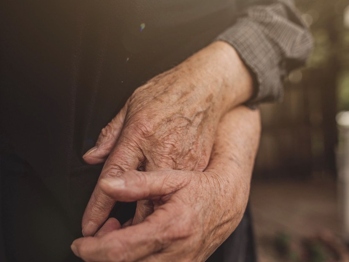 One hand resting gently over an older hand, in warm light