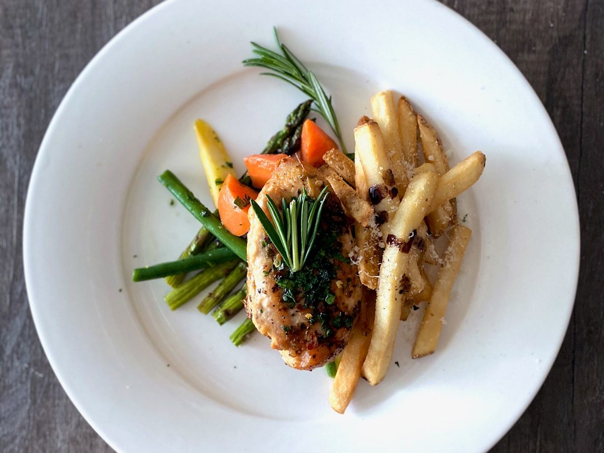 A freshly plated herb chicken dinner with seasonal vegetables